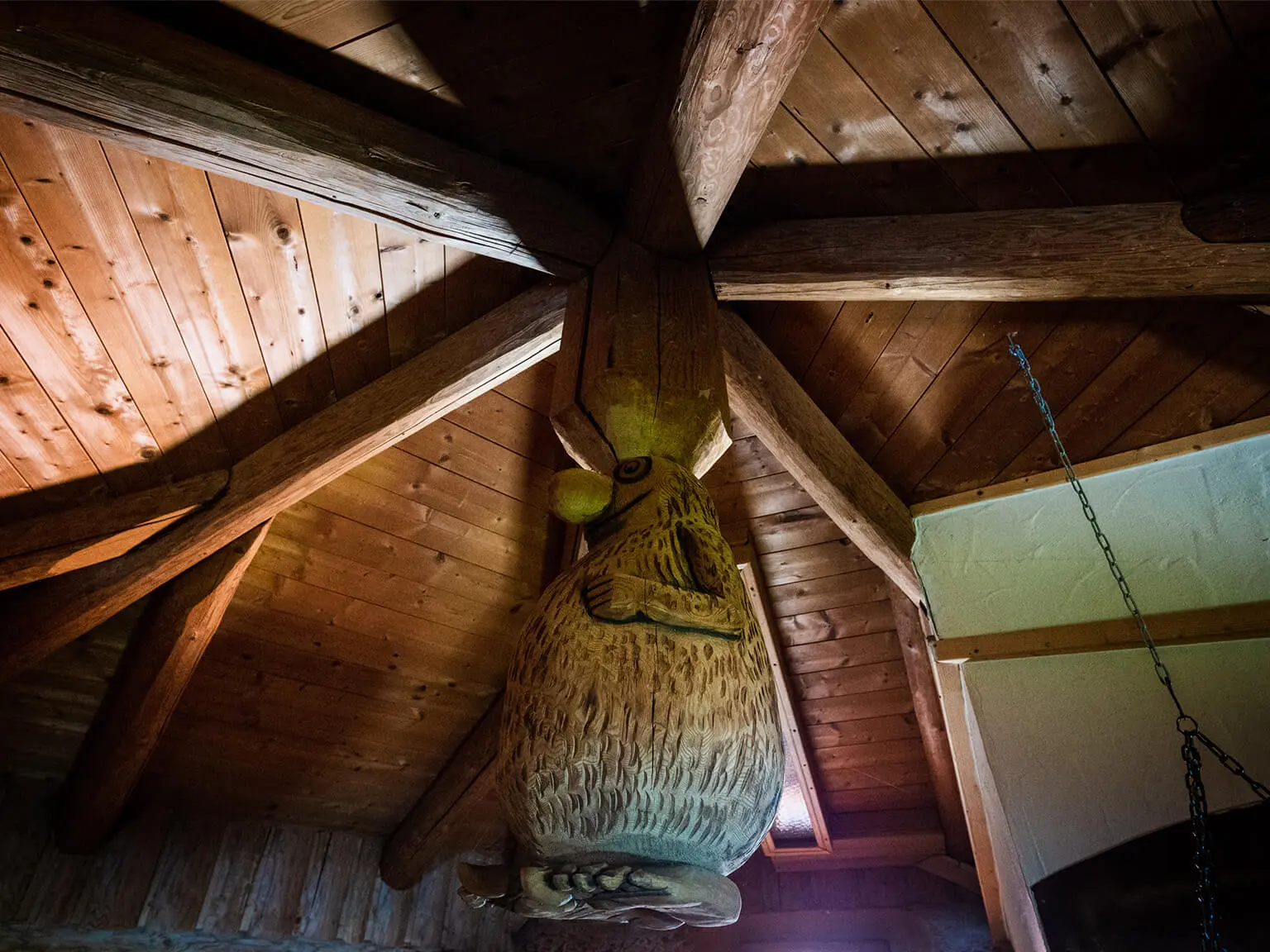Innenansicht einer Sauna. Blick ins Dach mit einem hölzernen Knubbelmännchen - dicknasig und behaart -als Saunamaskottchen.