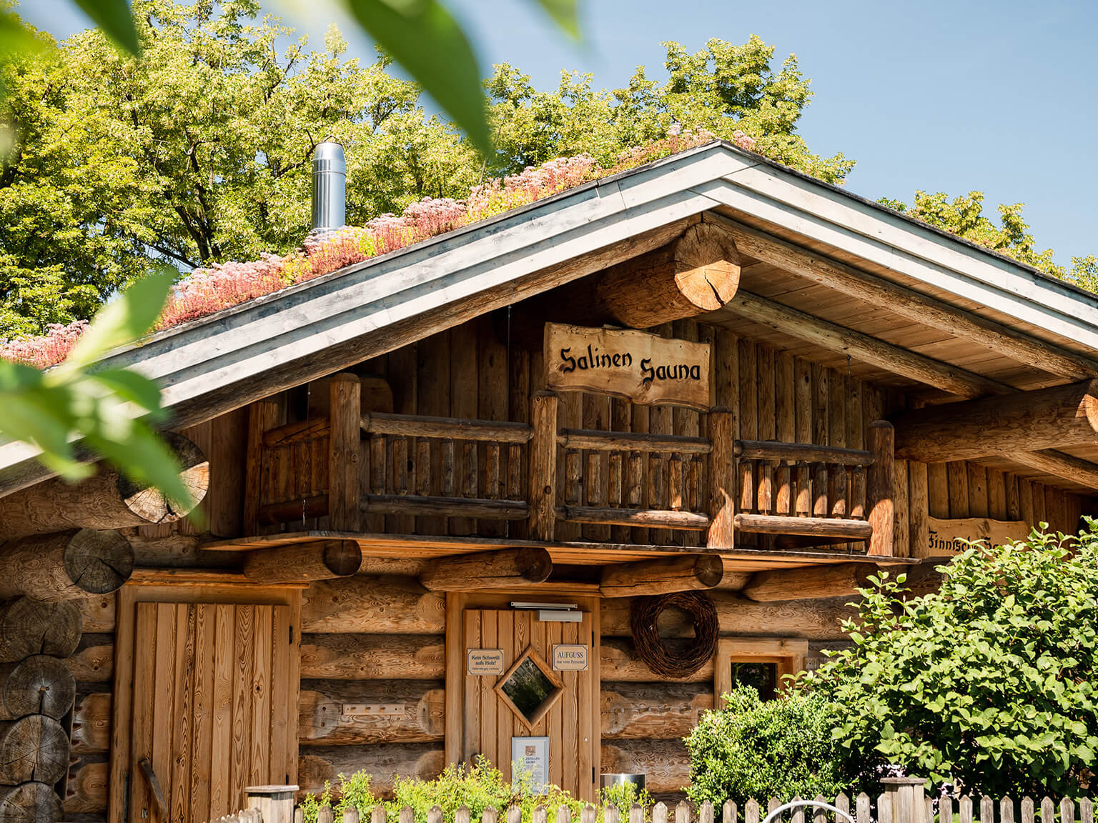 Nahaufnahme der Salinen-Sauna mit Blick auf die Holzbauweise und das Grasdacht. Ringsherum Grün.